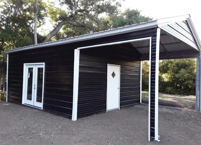 A sleek black metal utility building featuring a white-trimmed enclosed storage room with a gabled glass-pane entry door and an attached open side carport cover for flexible vehicle parking