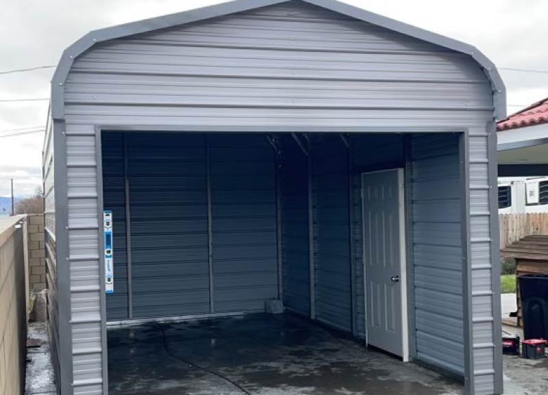 Fully enclosed modern gray metal garage building with a wide open front entry and a white side access door.