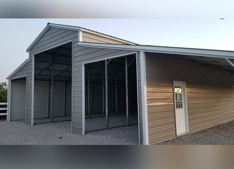 Large premium steel step-down barn building featuring open parking bays and a white paneled walk-in access door.