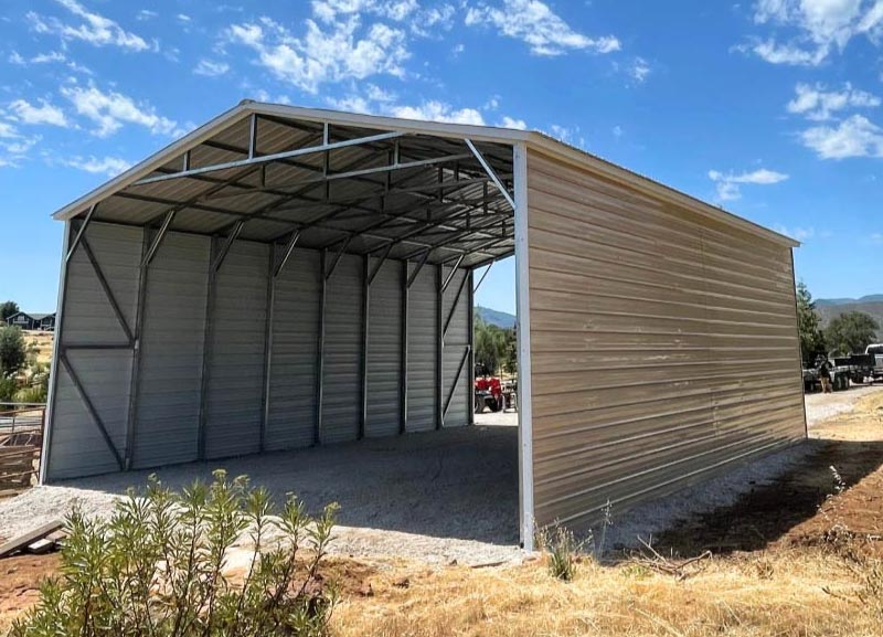 Fully enclosed tan A-frame vertical steel RV garage building with a concrete foundation and open front drive bay entry.