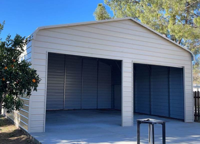 Off-white custom double steel carport garage building with two open parking bays installed on a concrete foundation pad.